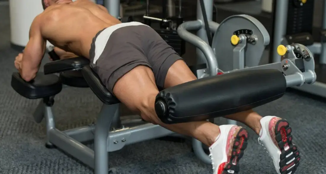 Homem fazendo flexão de perna na máquina.