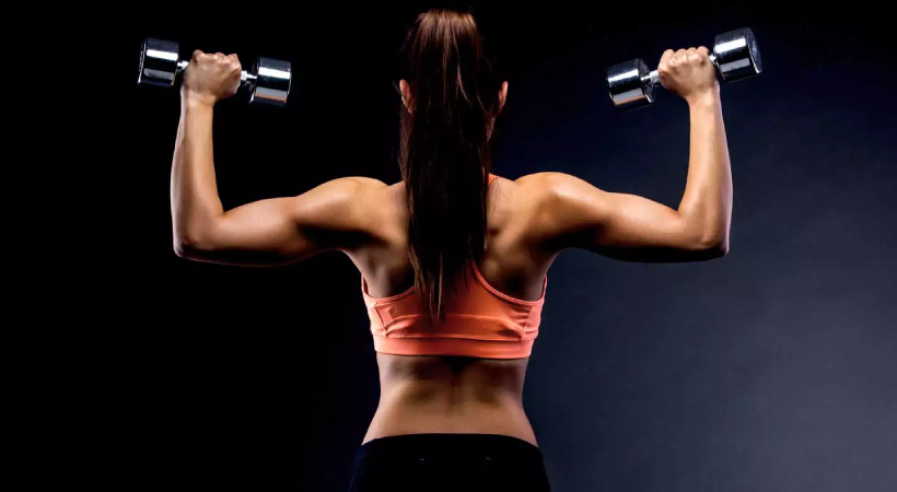 Mulher mostrando na academia como dividir treino de superiores de forma completa e funcional.